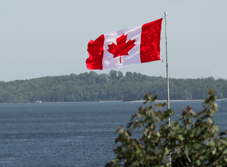 An image of a sunny lake view in Canada with forest in distance and a Canadian flag waving in wind in right corner.
